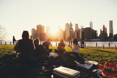 A group of people having a picnic in a city park at dusk.